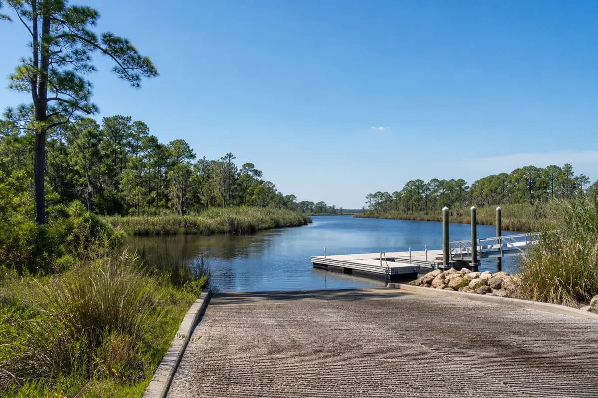 An illustration of a public boat landing on a narrow, tea-coloured creek lined with cypress and marsh grass, a small floating dock, for Black Creek Boat Ramp