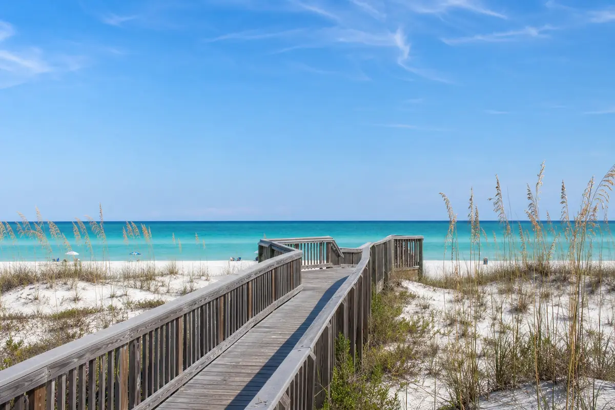A public beach access boardwalk crossing white sand dunes with sea oats, emerald Gulf water beyond: an illustration for Santa Rosa Beach's beach tile.